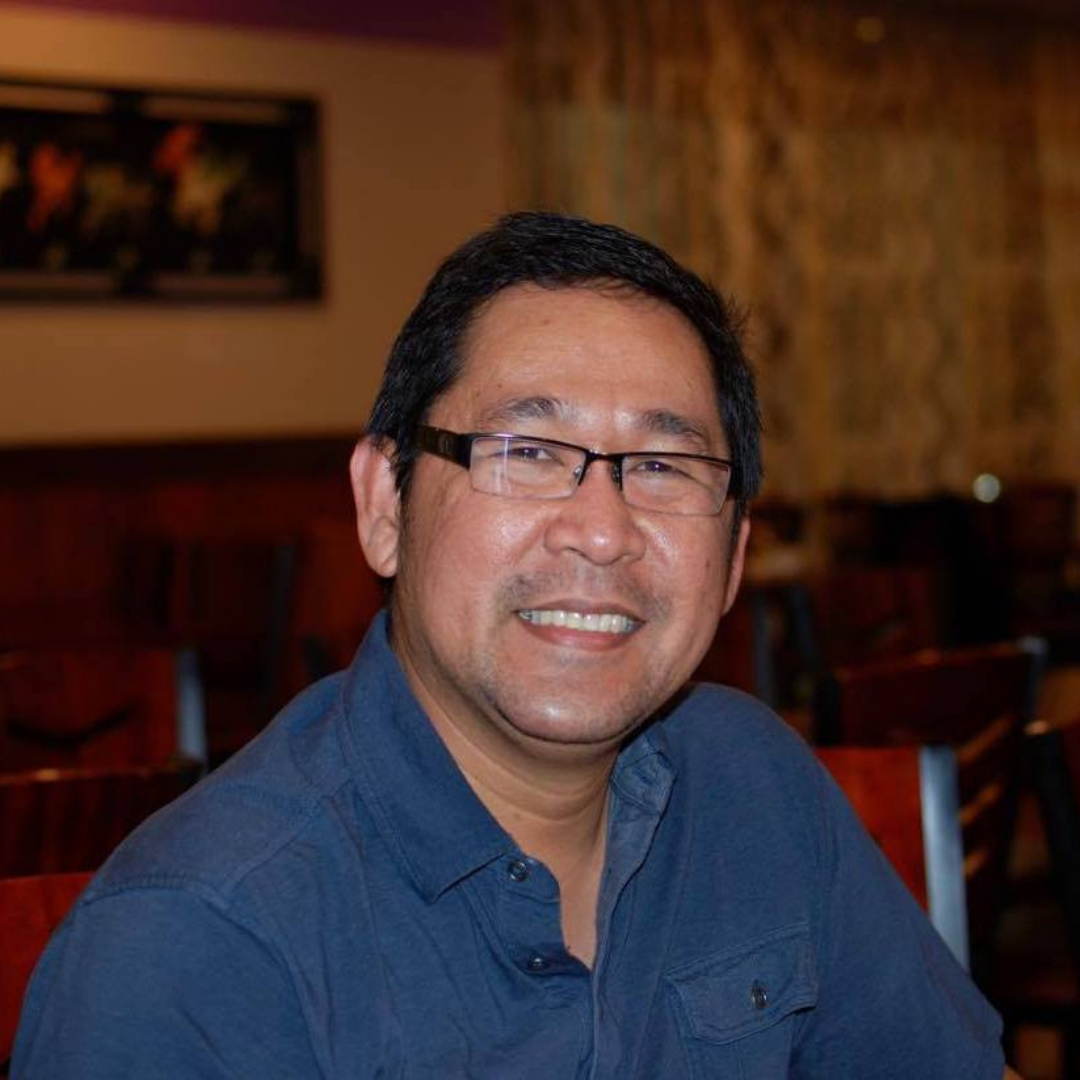 A smiling man wearing glasses and a blue shirt